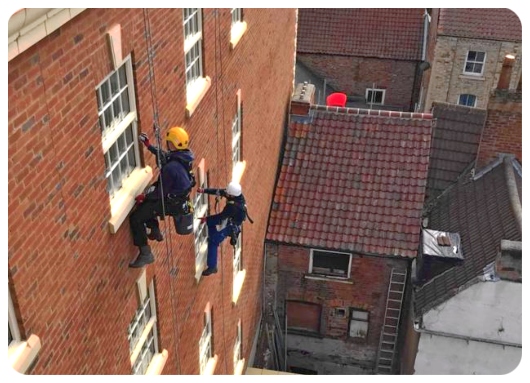 Image of co,mmercial window cleaing in action abseiling to reach to the high level windows 