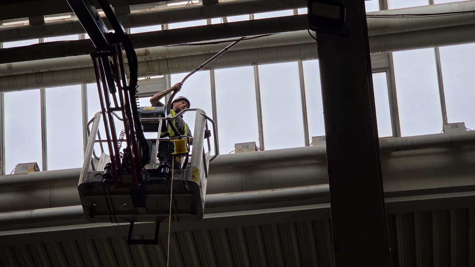High-Level Cleaning and Dust Removal with Long Reach Pole High-reach platform worker cleaning industrial pipes inside a industrial setting