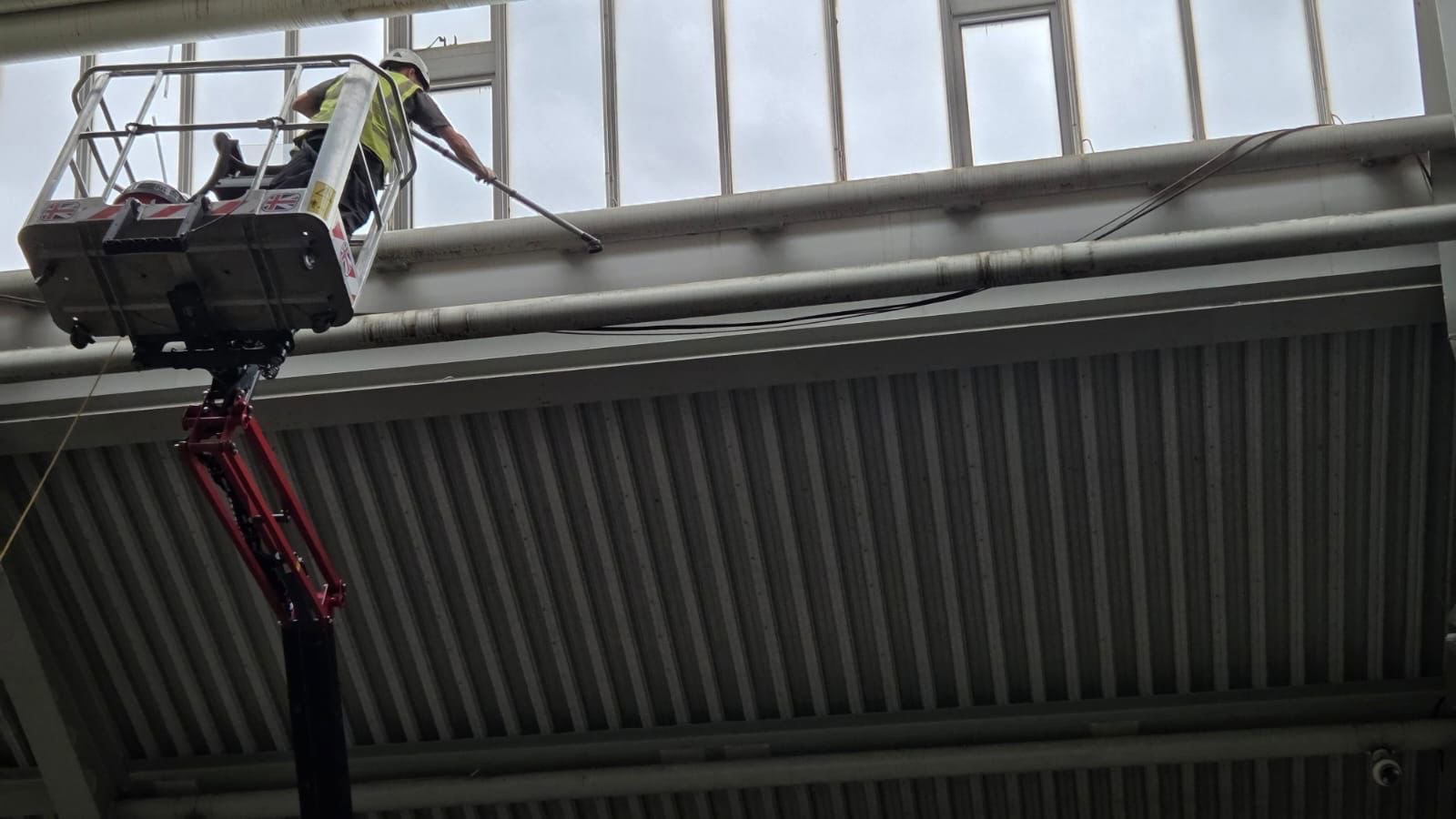 High-Level Vacuum Cleaning Steel Beams Premium industrial cleaning and painting services at Brooklands Group. Cleaning Internal high-level pipes in Industrial setting using powered access platforms cherry picker.