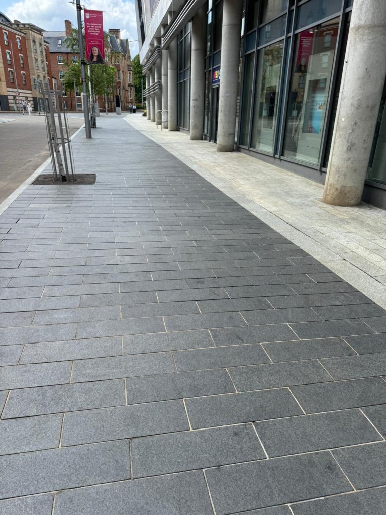Clear and clean modern city pavement with dark and light grey tiles in front of a commercial building, showcasing professional cleaning and maintenance services provided by Brooklands.