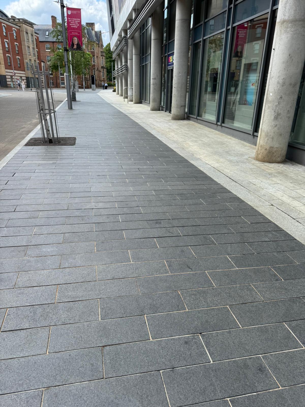 Clear and clean modern city pavement with dark and light grey tiles in front of a commercial building, showcasing professional cleaning and maintenance services provided by Brooklands.