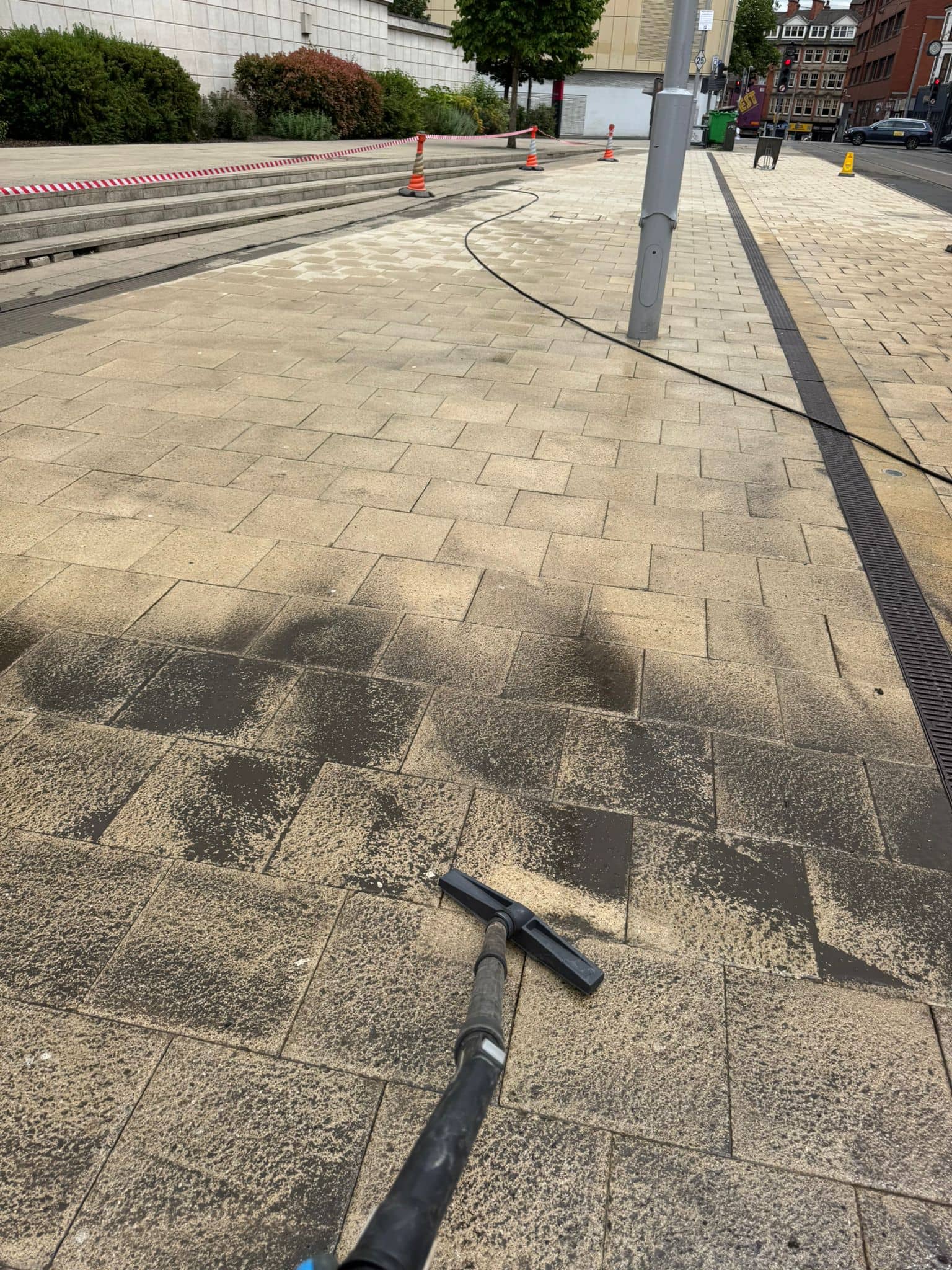 Pavement cleaning to rmove oil spill with a power washer, showing the removal of dirt and grime from paving stones.