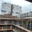 Outdoor building scaffolding with brick cleaning technitian cleaning brick on high rise building under cloudy sky.