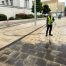 High-pressure cleaning worker jet washing pavement at a university building in Nottingham to remove oil spill, dirt and grime from paving.