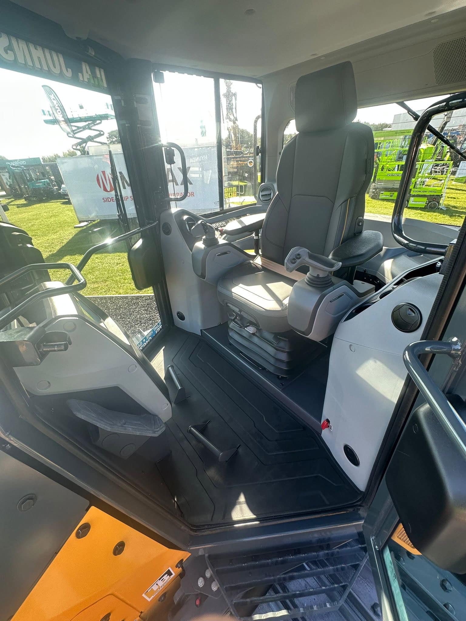 High-quality image of a modern construction excavator cab with ergonomic controls and comfortable seating, showcasing professional machinery used for groundworks, earthmoving, and site preparation. Image taken outdoors at a machinery showroom. The machinery has recently been cleaned by Brooklands Group.