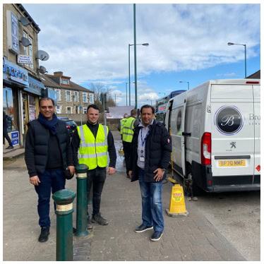 Professional team of street cleaners and local authority officials in high-visibility vests outside a commercial building, preparing for on-site street cleansing services