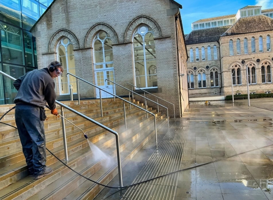 High-pressure cleaning of outdoor steps and handrails at a historic building.