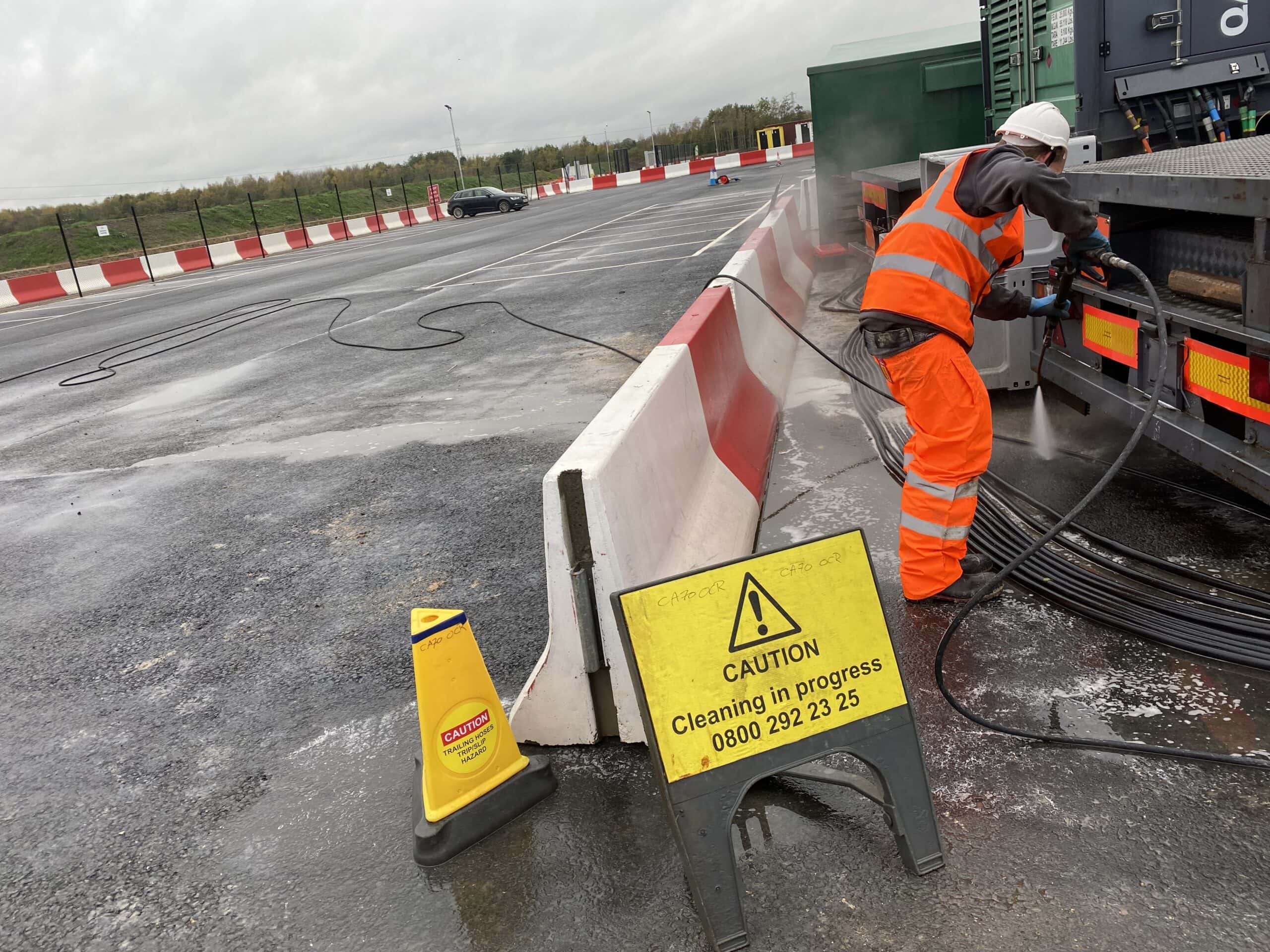 High-visibility worker cleaning tarmac surface to remove a sutance spillage