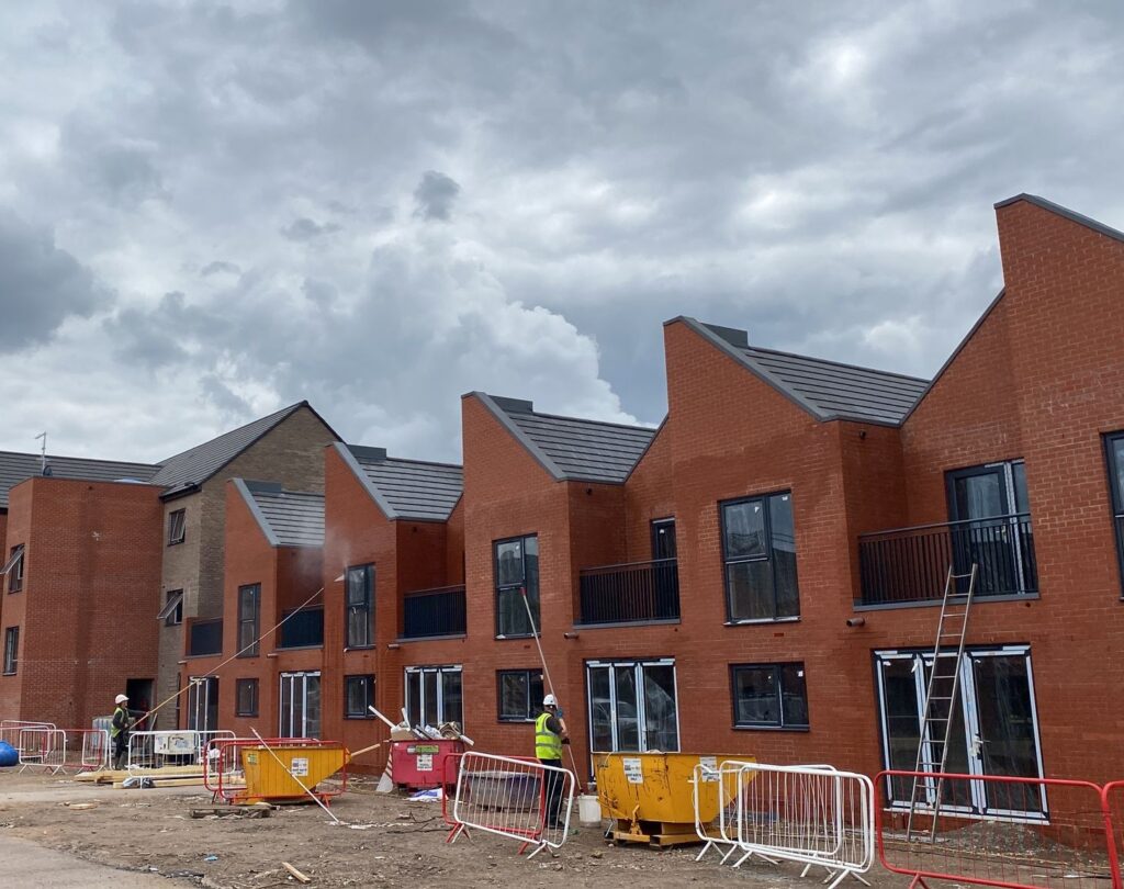 Brick and stone building exterior being cleaned with scaffolding and workers present.